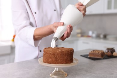 Photo of Professional pastry chef making cake at table in kitchen, closeup