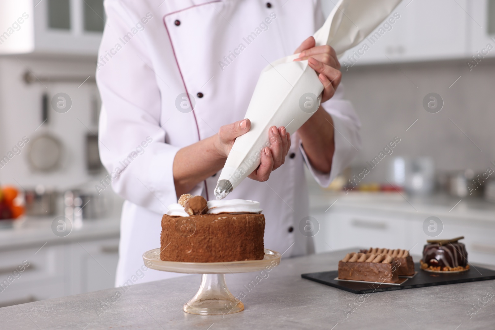 Photo of Professional pastry chef making cake at table in kitchen, closeup