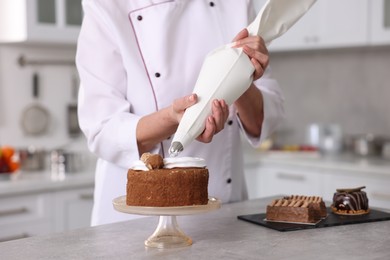 Photo of Professional pastry chef making cake at table in kitchen, closeup