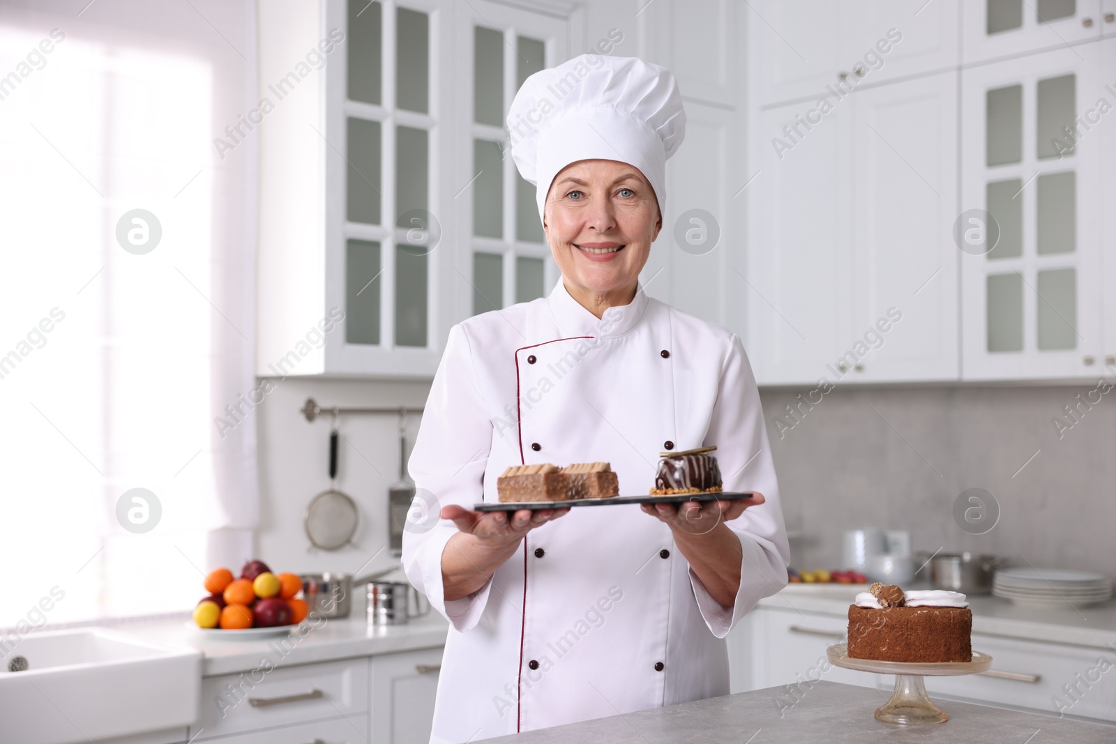 Photo of Professional pastry chef with desserts at table in kitchen