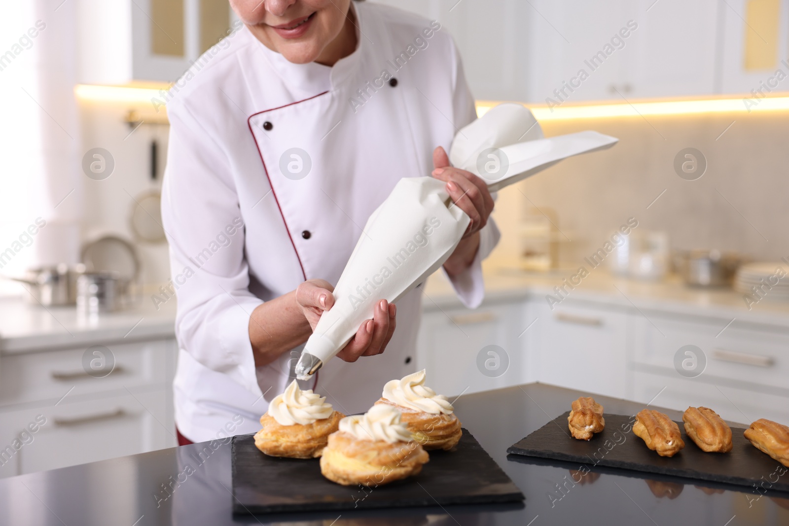 Photo of Professional pastry chef making desserts at table in kitchen, closeup