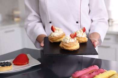 Photo of Professional pastry chef with desserts at table in kitchen, closeup