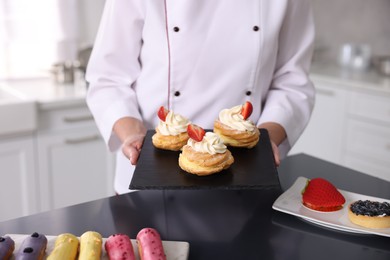 Photo of Professional pastry chef with desserts at table in kitchen, closeup