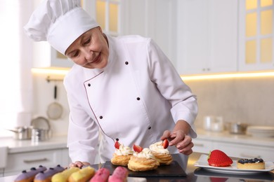 Photo of Professional pastry chef making desserts at table in kitchen