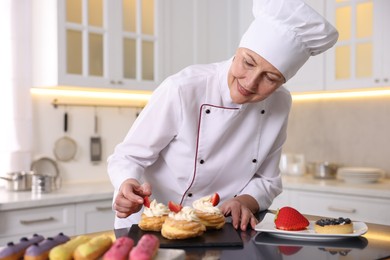 Professional pastry chef making desserts at table in kitchen