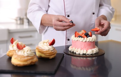 Photo of Professional pastry chef making cake at table in kitchen, closeup