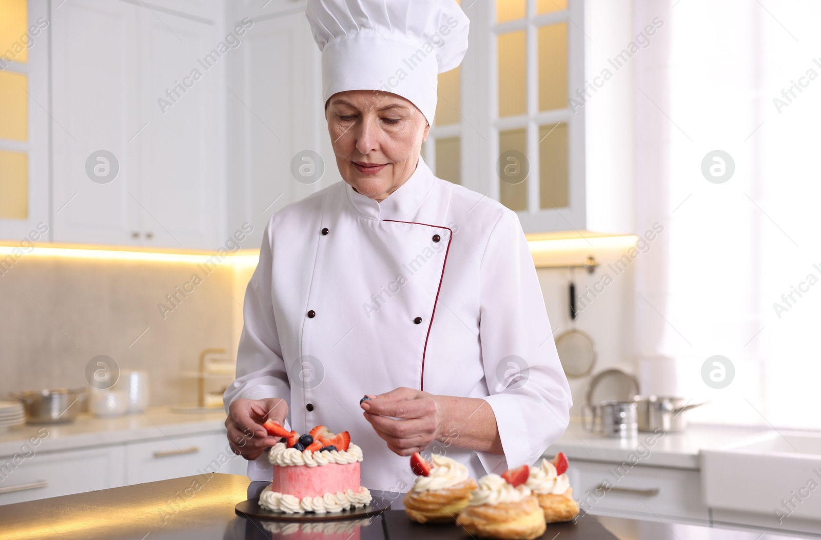 Photo of Professional pastry chef with desserts at table in kitchen