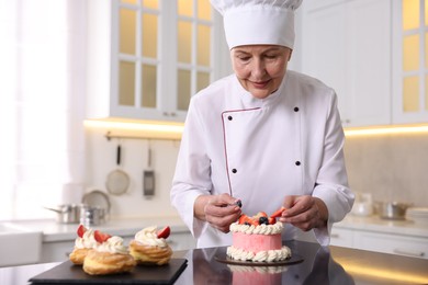 Photo of Professional pastry chef making cake at table in kitchen