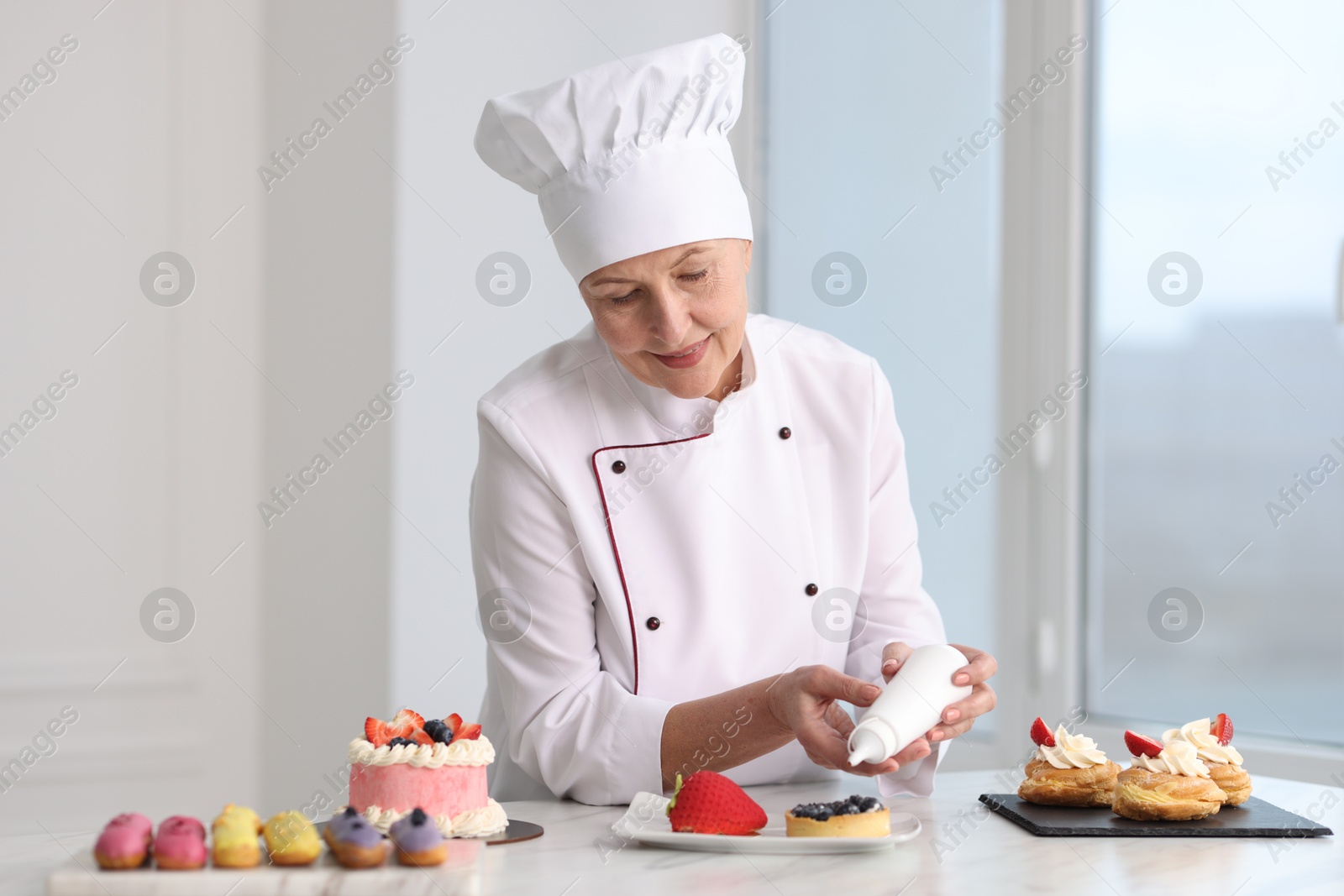 Photo of Professional pastry chef making desserts at table in kitchen