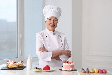 Professional pastry chef with desserts at table in kitchen