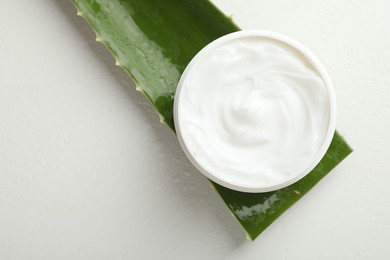 Photo of Moisturizing cream with extract of aloe vera and cut leaf on white textured background, top view. Space for text