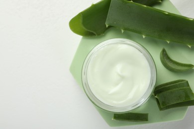 Photo of Moisturizing cream with extract of aloe vera and cut leaves on white background, flat lay. Space for text