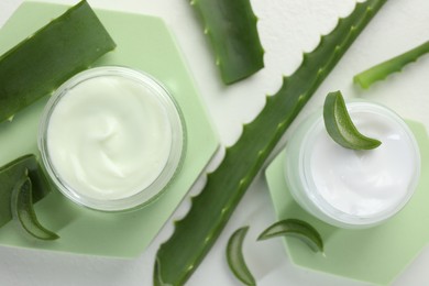 Photo of Moisturizing cream with extract of aloe vera and cut leaves on white background, flat lay