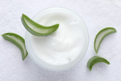 Photo of Moisturizing cream with extract of aloe vera and cut leaves on white towel, top view