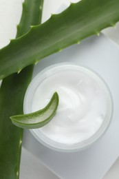 Photo of Moisturizing cream with extract of aloe vera and cut leaves on white background, flat lay