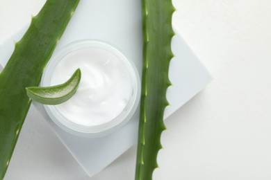 Photo of Moisturizing cream with extract of aloe vera and cut leaves on white background, flat lay