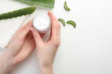 Photo of Woman with moisturizing cream, aloe vera leaves and towel at white textured table, top view. Space for text