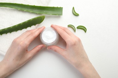 Photo of Woman with moisturizing cream, aloe vera leaves and towel at white textured table, top view