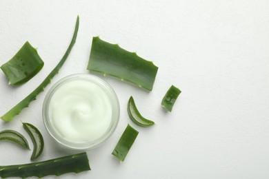 Photo of Moisturizing cream with extract of aloe vera and cut leaves on white textured background, flat lay. Space for text