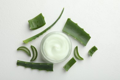 Photo of Moisturizing cream with extract of aloe vera and cut leaves on white textured background, flat lay