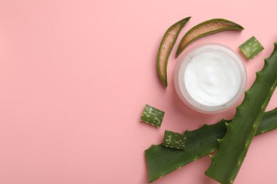 Moisturizing cream with extract of aloe vera in jar and cut leaves on pink background, flat lay. Space for text