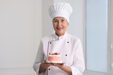 Professional pastry chef with cake in kitchen