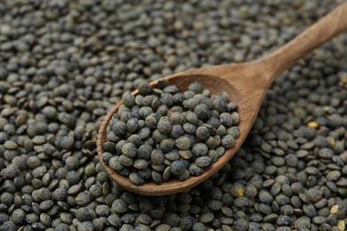 Photo of Raw green lentils and spoon as background, closeup view