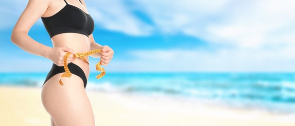 Get fit for summer. Woman with measuring tape showing her slim body on beach, closeup. Banner design with space for text