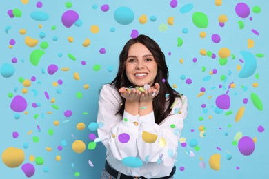 Image of Happy woman under falling confetti on light blue background. Surprise party