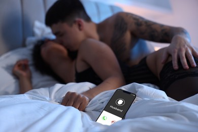 Image of Betrayal. Husband calling his wife on phone, while she spending time with other man on bed, selective focus