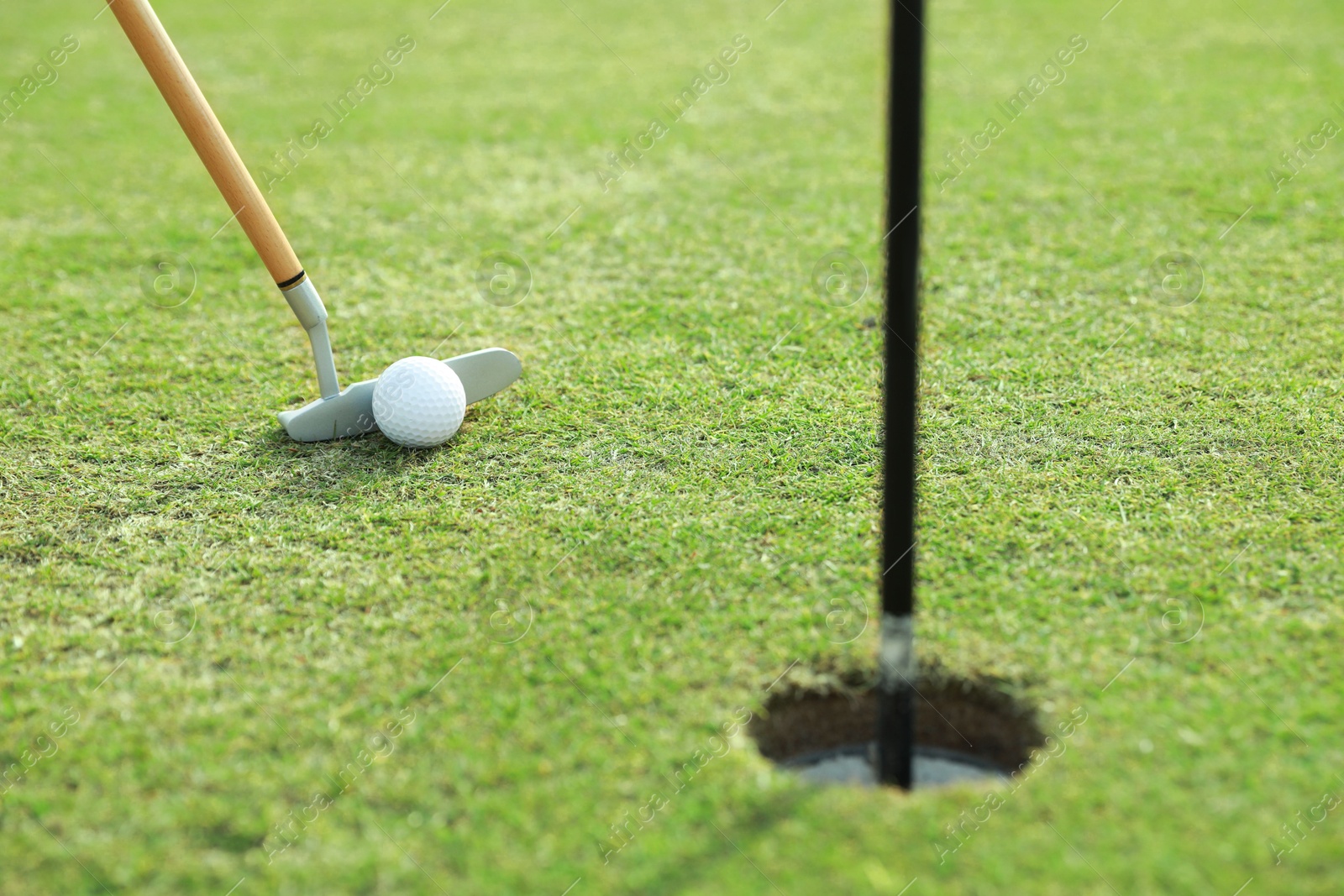 Photo of Hitting golf ball with club on green course