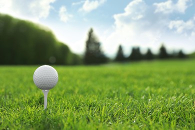 Golf ball on tee at green course, space for text