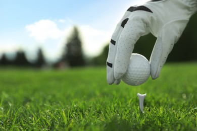 Photo of Golfer putting ball on tee at green course, closeup. Space for text