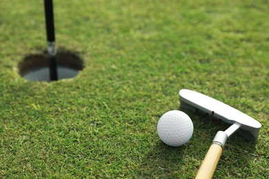 Photo of Golf ball and club near hole on green course