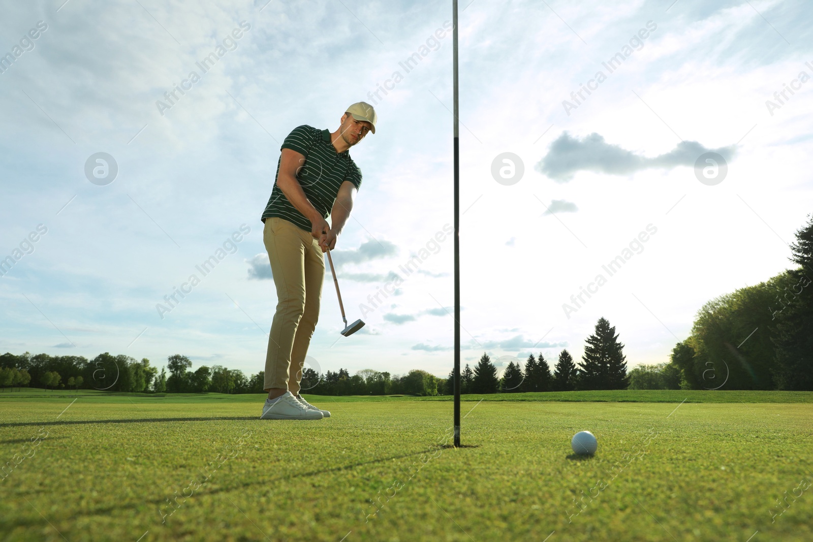 Photo of Man playing golf at green course on sunny day