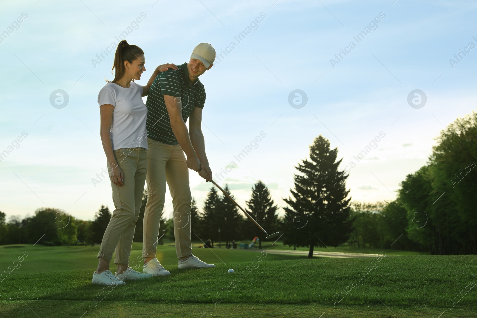 Photo of Happy couple playing golf on green course, space for text