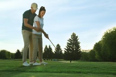 Photo of Man teaching his girlfriend to play golf on green course