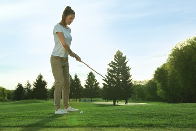 Beautiful woman playing golf on green course, space for text