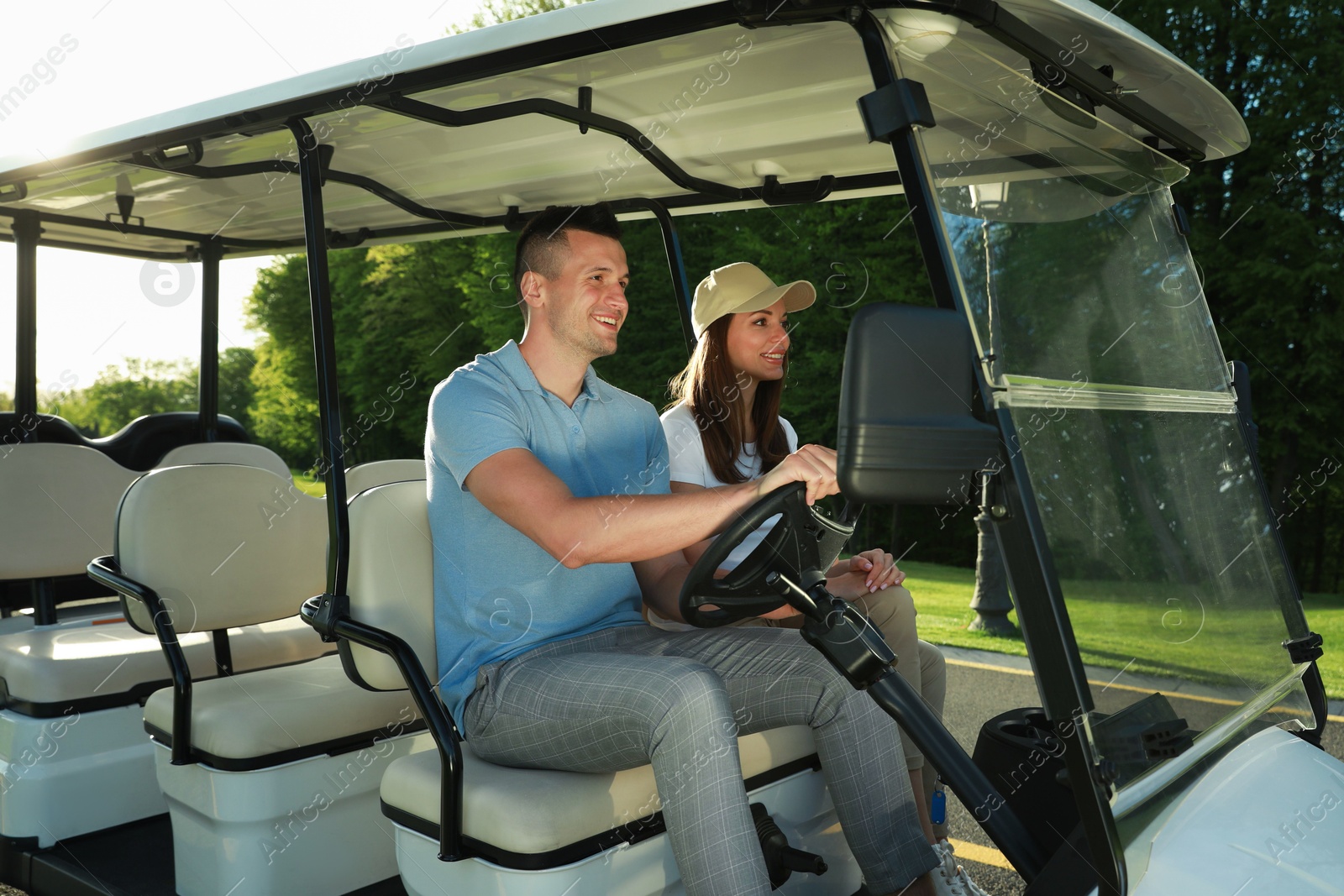 Photo of Happy couple driving golf cart in park