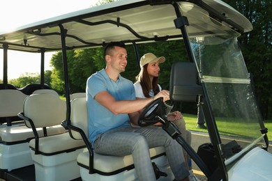 Happy couple driving golf cart in park