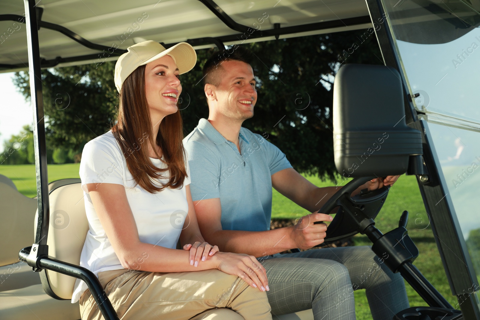 Photo of Happy couple driving golf cart in park