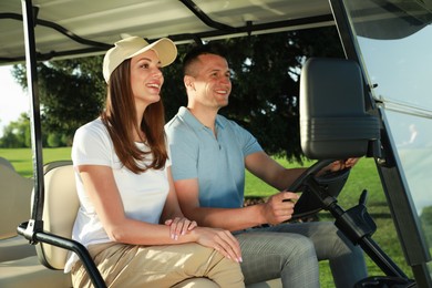 Happy couple driving golf cart in park