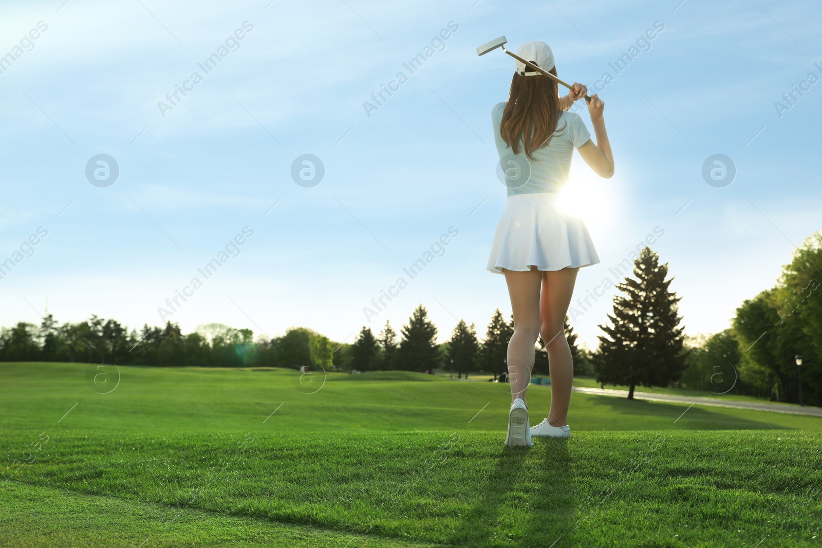 Photo of Woman playing golf on green course, back view. Space for text