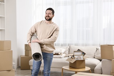 Moving day. Happy man with rug in his new home