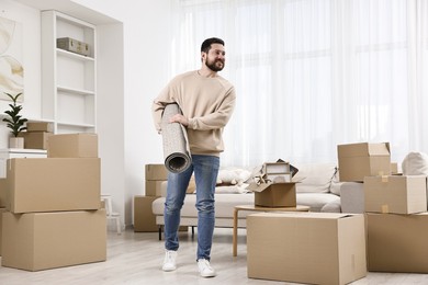 Photo of Moving day. Happy man with rug in his new home