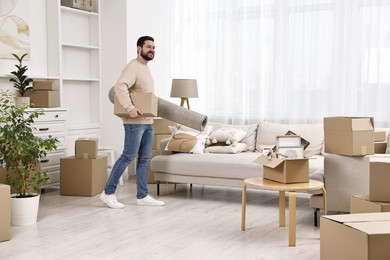 Moving day. Happy man with rug and cardboard box in his new home