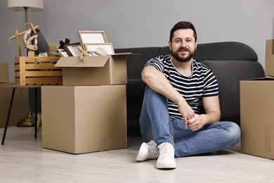 Moving day. Man resting on floor near cardboard boxes in his new home