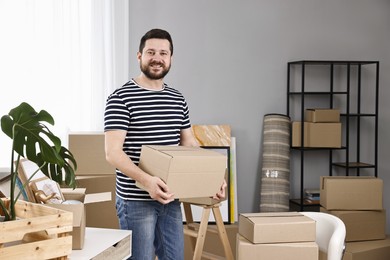 Photo of Moving day. Man with cardboard box in his new home