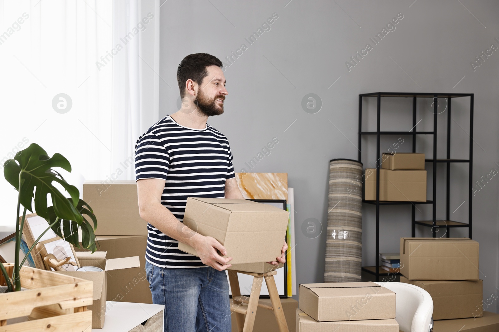 Photo of Moving day. Man with cardboard box in his new home