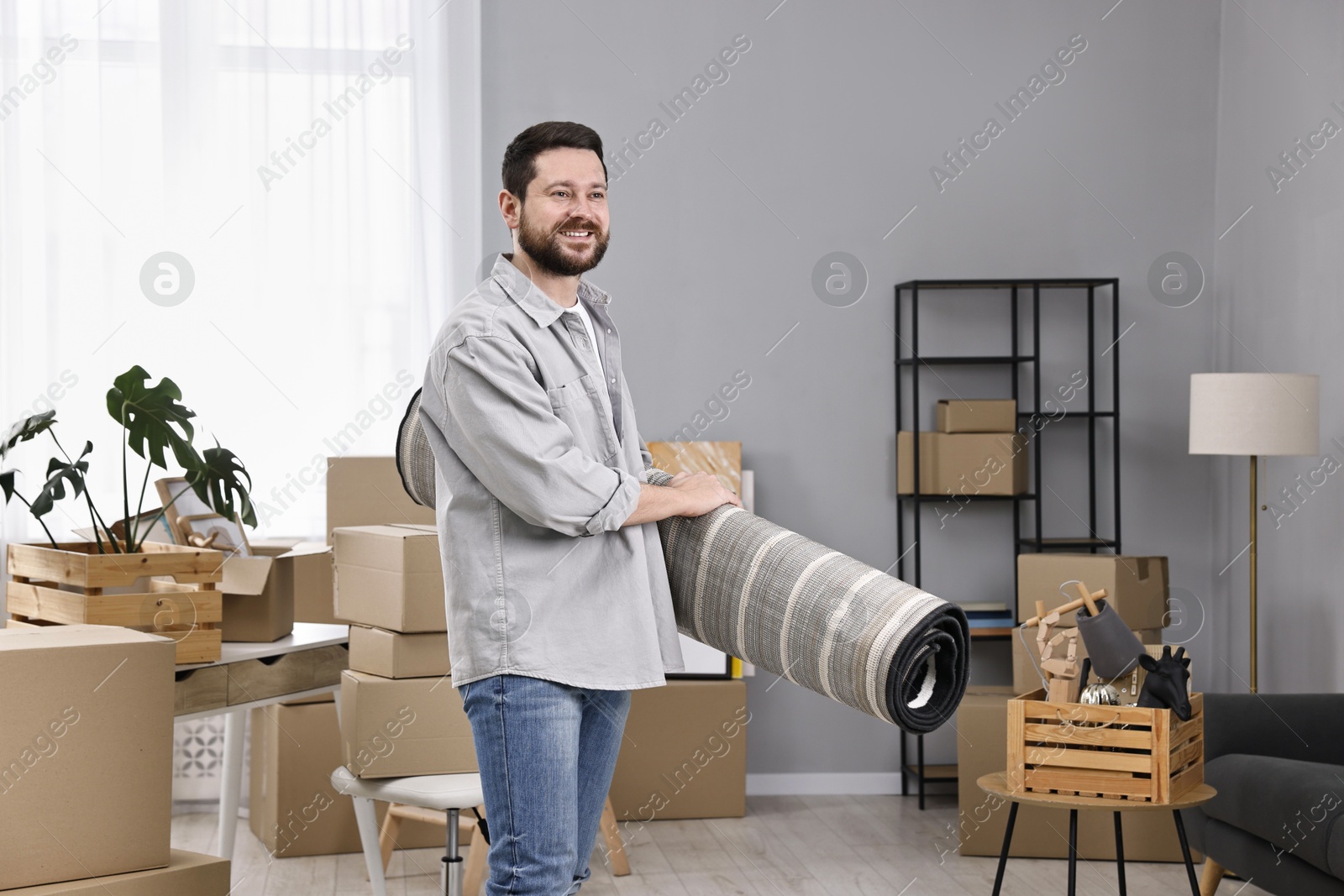 Photo of Moving day. Man with rug in his new home